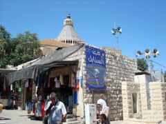 Steeple of the Church of Mary, with speakers of a small Mosque in the foreground, and shopping area (sy)